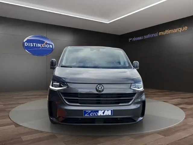 Vue frontale d'un Volkswagen Transporter gris foncé 2026 avec phares LED et logo VW bien visible.