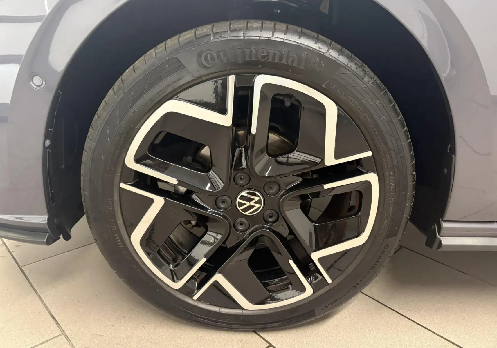 Gros plan sur la jante noire et argentée d'une Volkswagen Polo gris cendré, mettant en valeur le logo VW central.