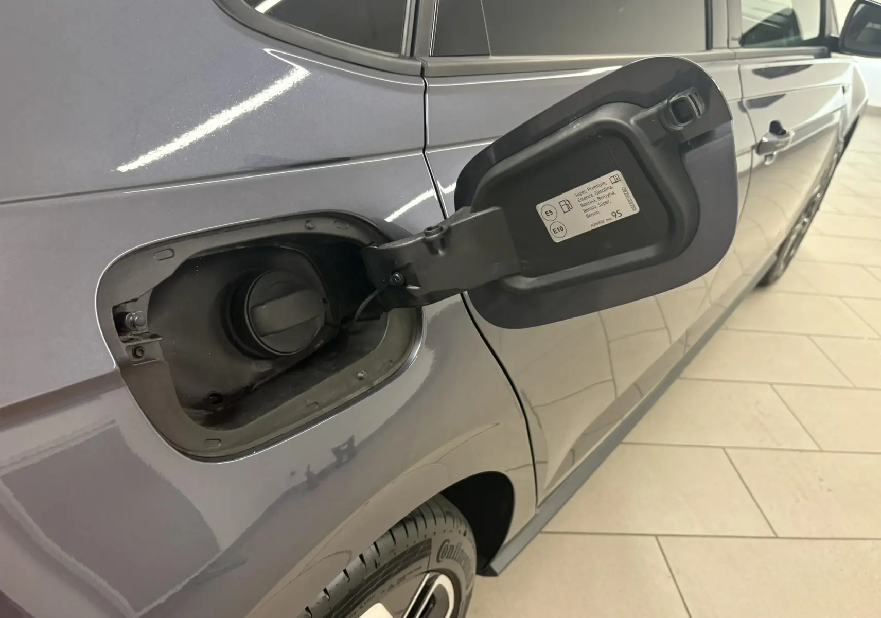 Vue latérale droite rapprochée d’une Volkswagen Polo gris cendré avec trappe à carburant ouverte montrant le bouchon essence.