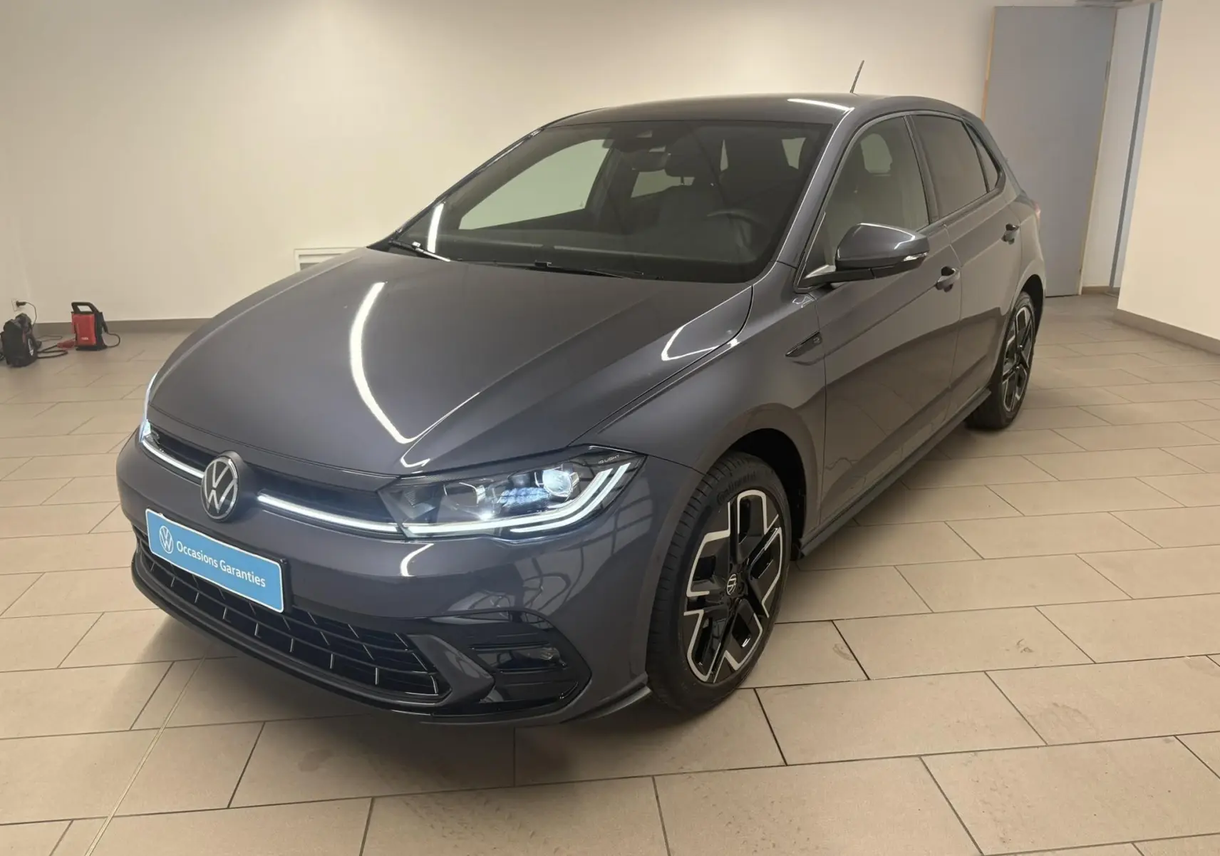 Volkswagen Polo 1.0 TSI R-Line gris cendré vue 3/4 avant droit en intérieur avec jantes spécifiques.