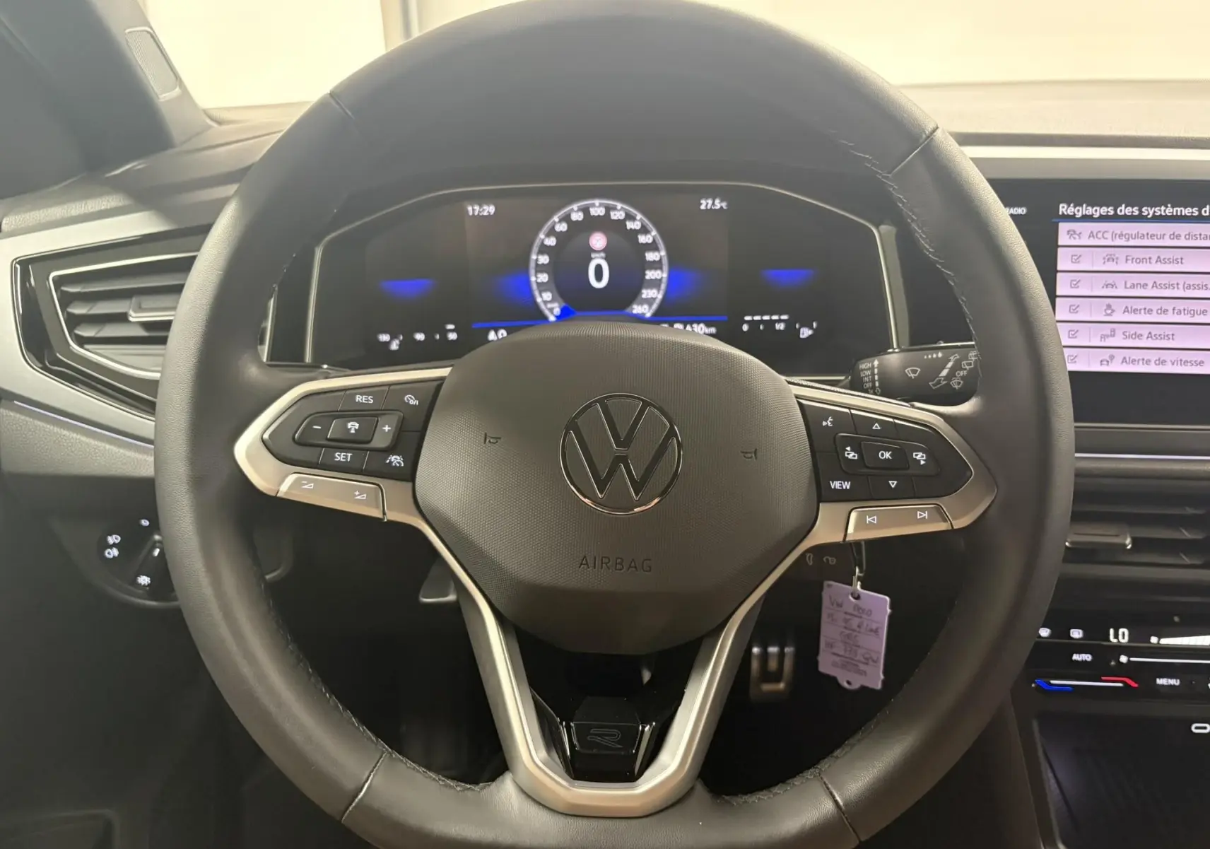 Vue rapprochée du volant noir de la Volkswagen Polo 1.0 TSI R-Line avec tableau de bord numérique allumé.