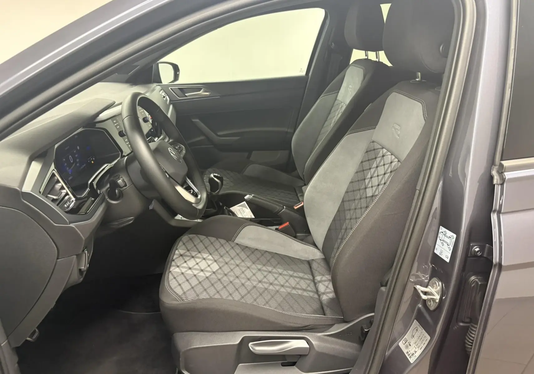 Intérieur côté conducteur de la Volkswagen Polo 1.0 TSI R-Line 2025 en gris cendré, sièges tissu avec motif et volant multifonction.