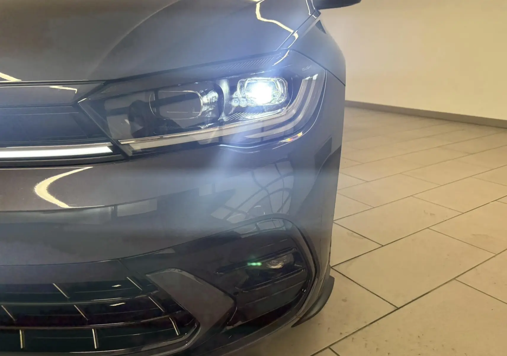 Gros plan sur le phare avant droit allumé d'une Volkswagen Polo 2025 gris cendré avec finition R-Line.