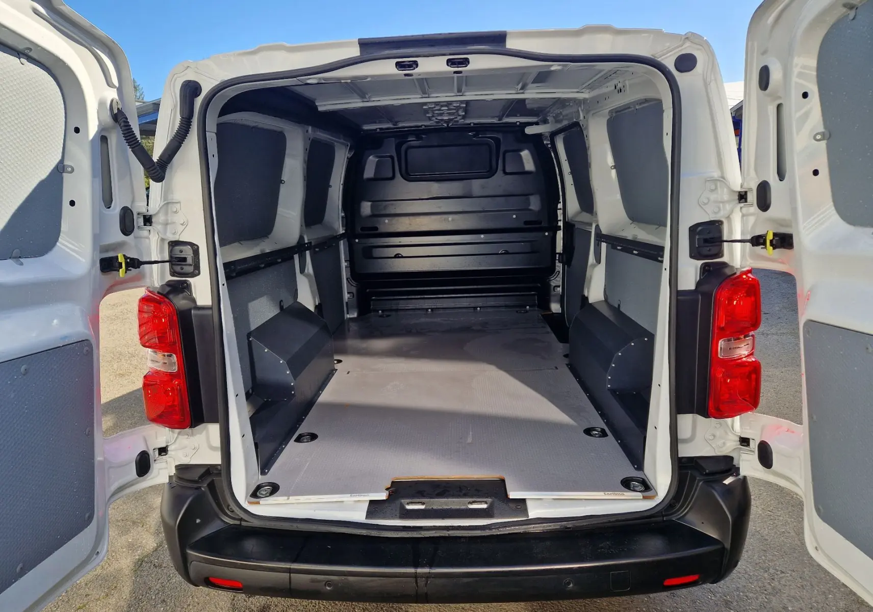 Vue arrière ouverte du fourgon blanc FIAT Scudo XL 2024, montrant l'espace de chargement vide et protégé.