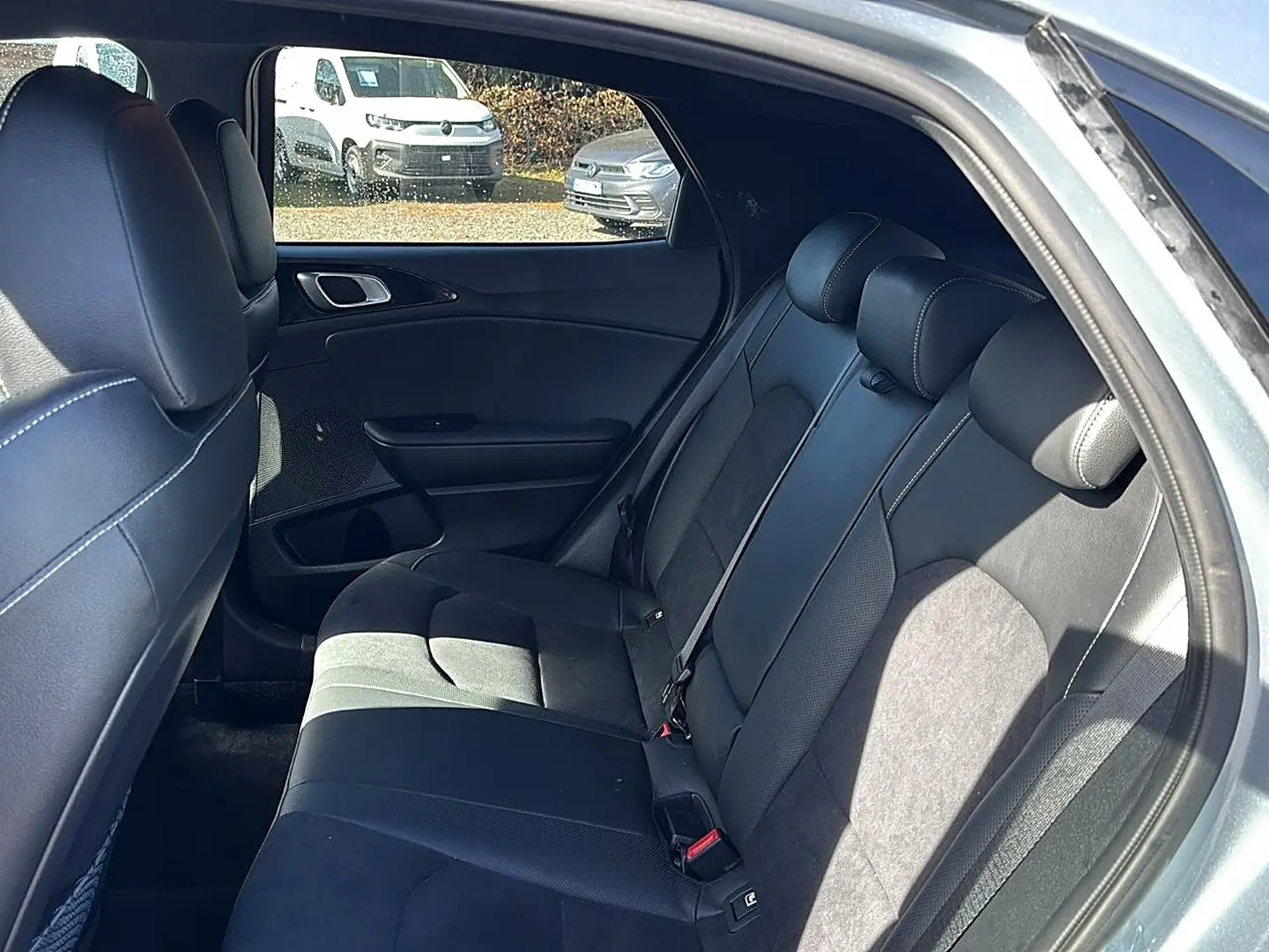 Vue intérieure côté droit des sièges arrière en tissu noir du Kia Xceed gris 2024 avec appuie-têtes et ceinture de sécurité.