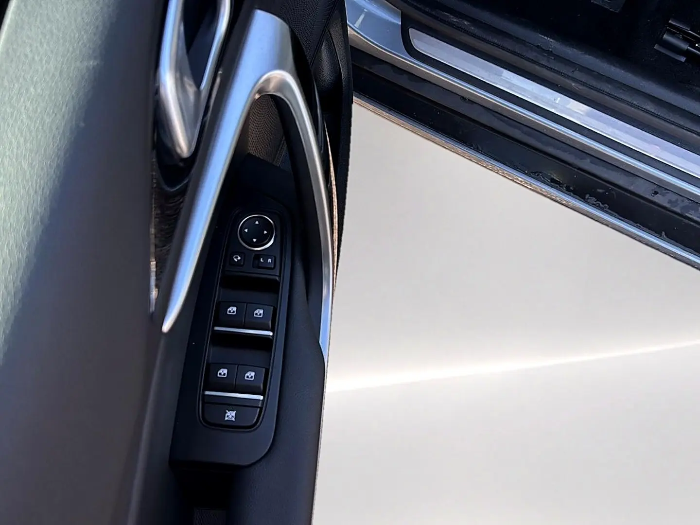 Gros plan sur la commande des vitres électriques côté conducteur d'une KIA Xceed gris 2024, avec poignée chromée.