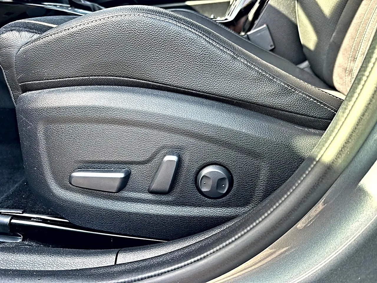 Gros plan sur les commandes de réglage électrique du siège conducteur en cuir noir du KIA Xceed gris 2024.