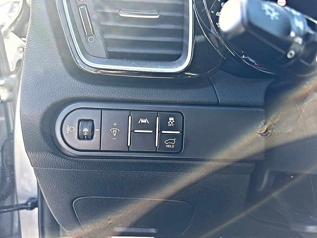 Gros plan sur les commandes d'assistance et réglages lumineux côté gauche du tableau de bord du KIA Xceed gris 2024.