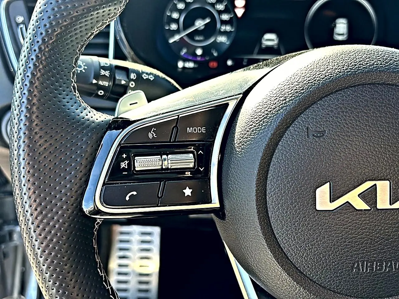 Gros plan sur le volant cuir perforé gris du Kia Xceed 2024, avec commandes multifonctions et palettes au volant.