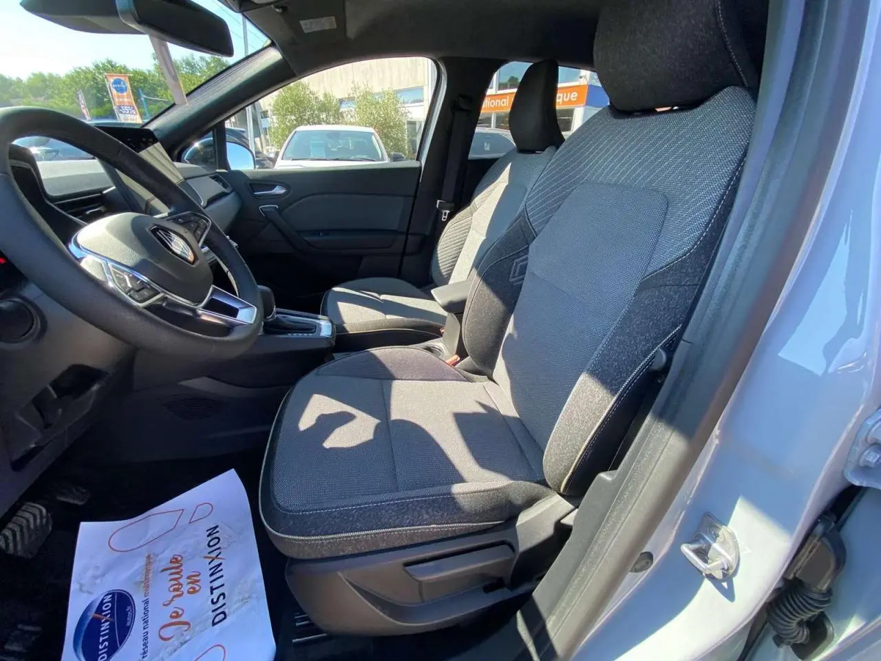 Vue intérieure côté conducteur du Renault Captur 2025 gris Rafale avec sièges tissu et volant multifonction.