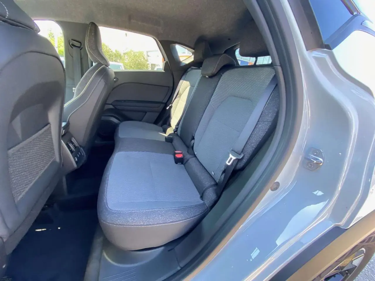 Vue côté droit de la banquette arrière grise du Renault Captur 2025 avec porte ouverte et sellerie tissu.