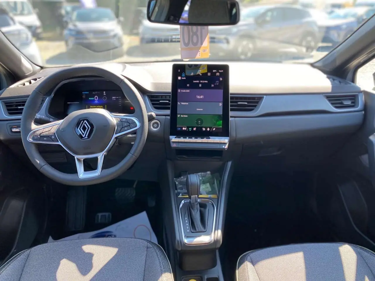 Vue intérieure avant du Renault Captur 2025, tableau de bord moderne avec écran tactile vertical et volant multifonction.