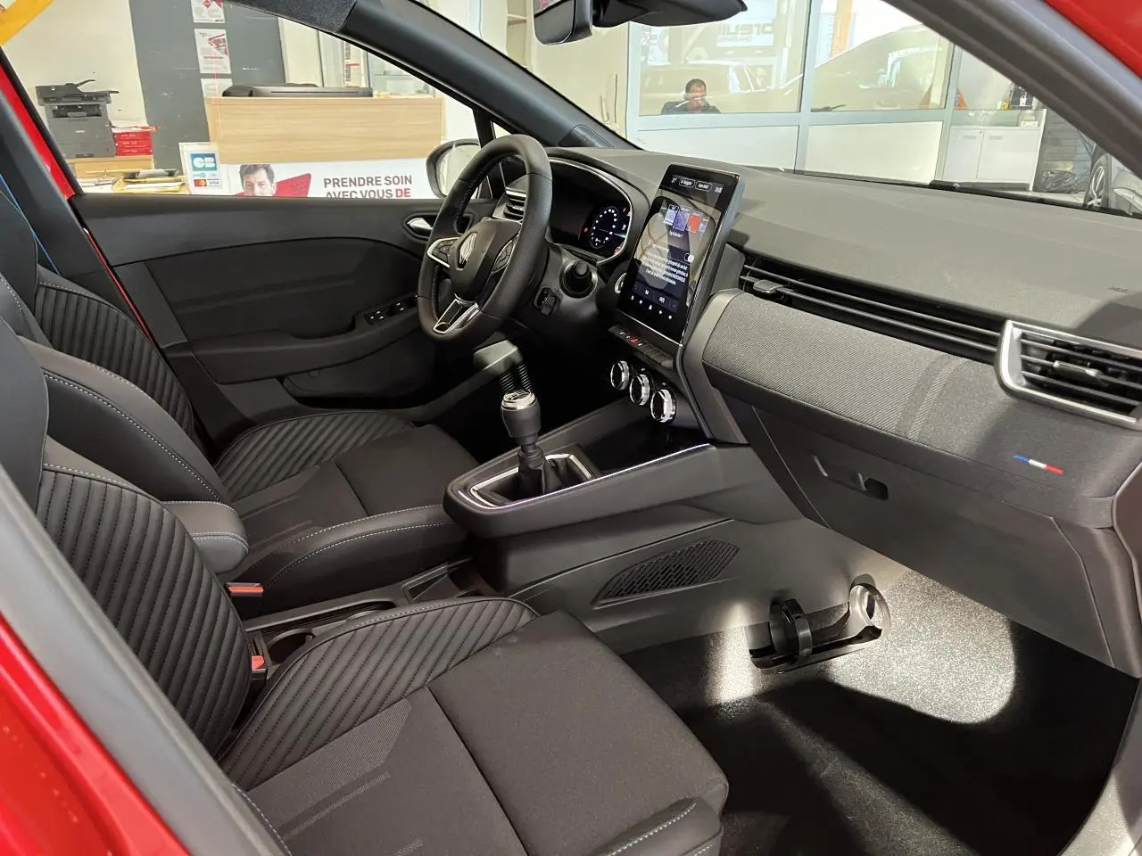 Intérieur avant de la Renault Clio 1.0 Tce 90 Esprit Alpine 2024 rouge, avec sièges noirs et console centrale moderne.
