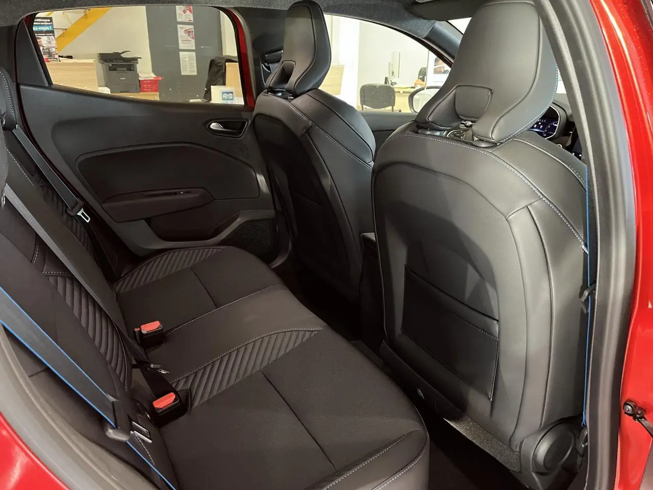Vue côté gauche de l'habitacle arrière de la Renault Clio 2024 rouge, sièges tissu noir avec surpiqûres bleues esprit Alpine.