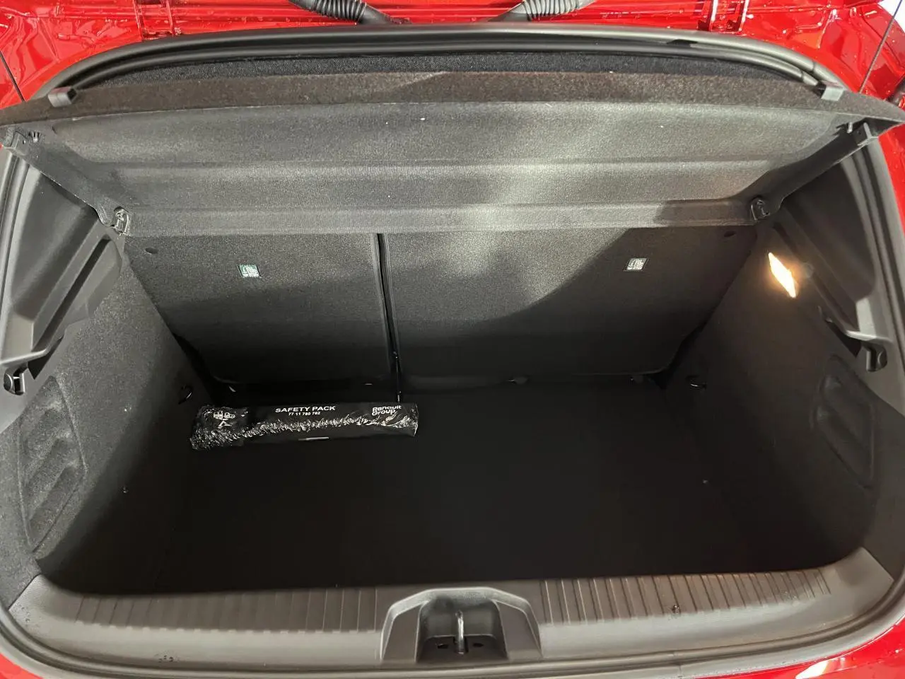 Coffre ouvert de la Renault Clio rouge 2024, montrant un espace de rangement propre avec kit de sécurité noir.