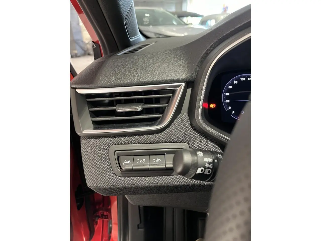 Détail de la console gauche avec aérateur chromé et commandes d'assistance sur Renault Clio rouge 2024 Esprit Alpine.