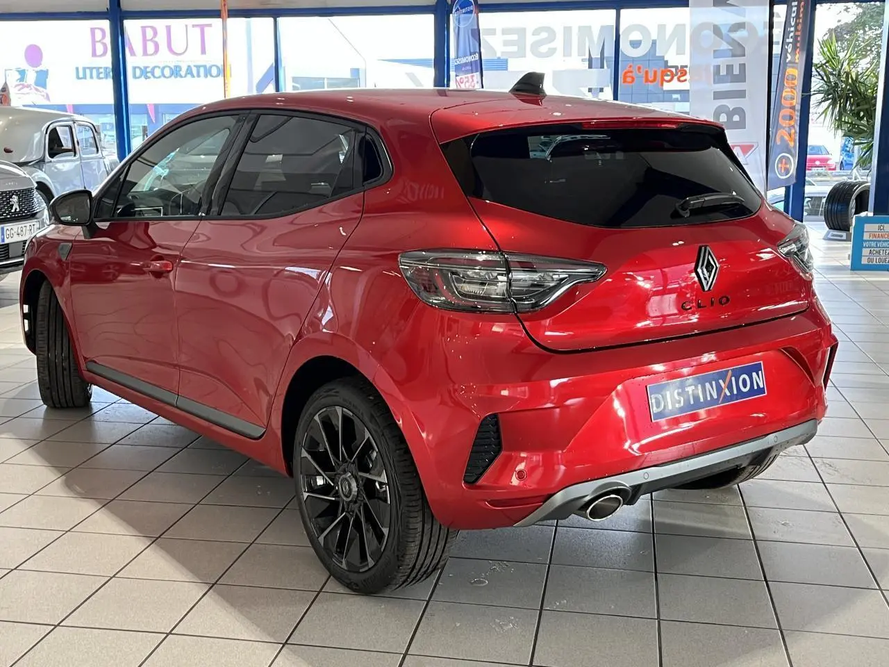 Vue 3/4 arrière droite d'une Renault Clio 1.0 Tce Esprit Alpine rouge, avec jantes noires et échappement chromé.