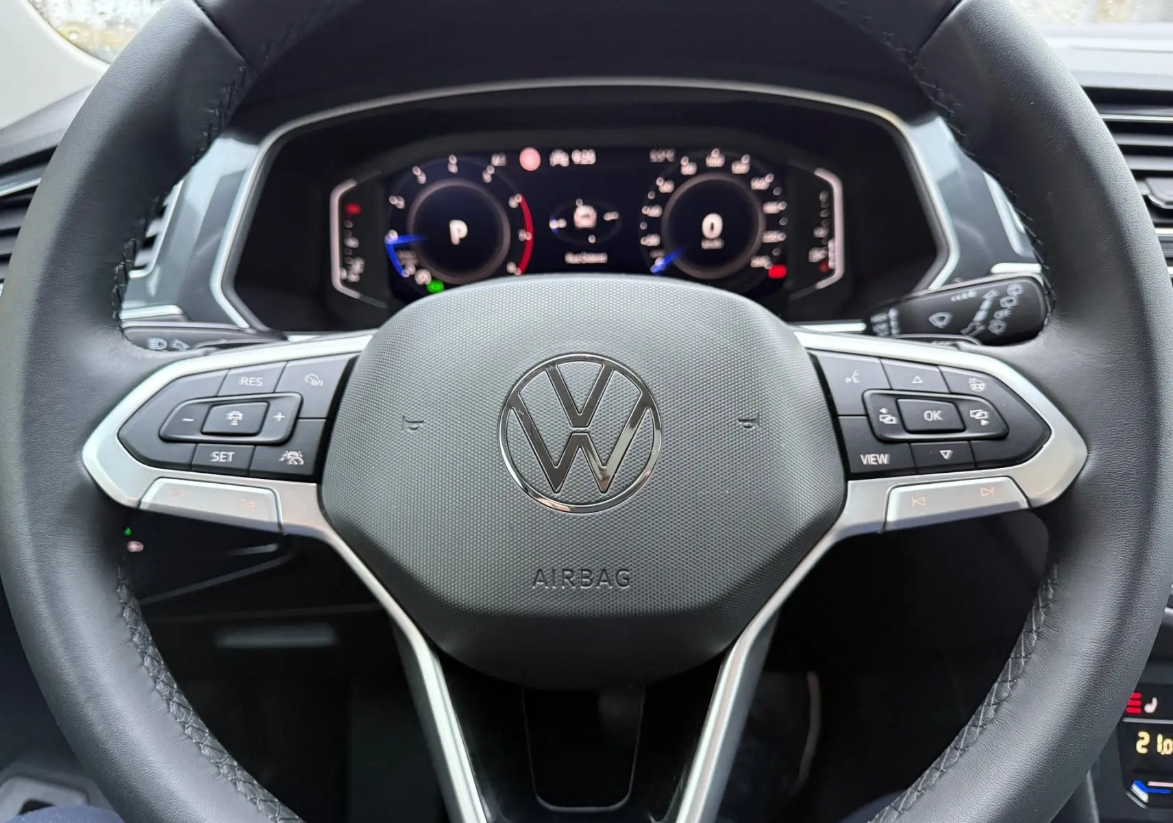 Vue rapprochée du volant noir du Volkswagen Tiguan 2022 avec commandes intégrées et tableau de bord numérique.