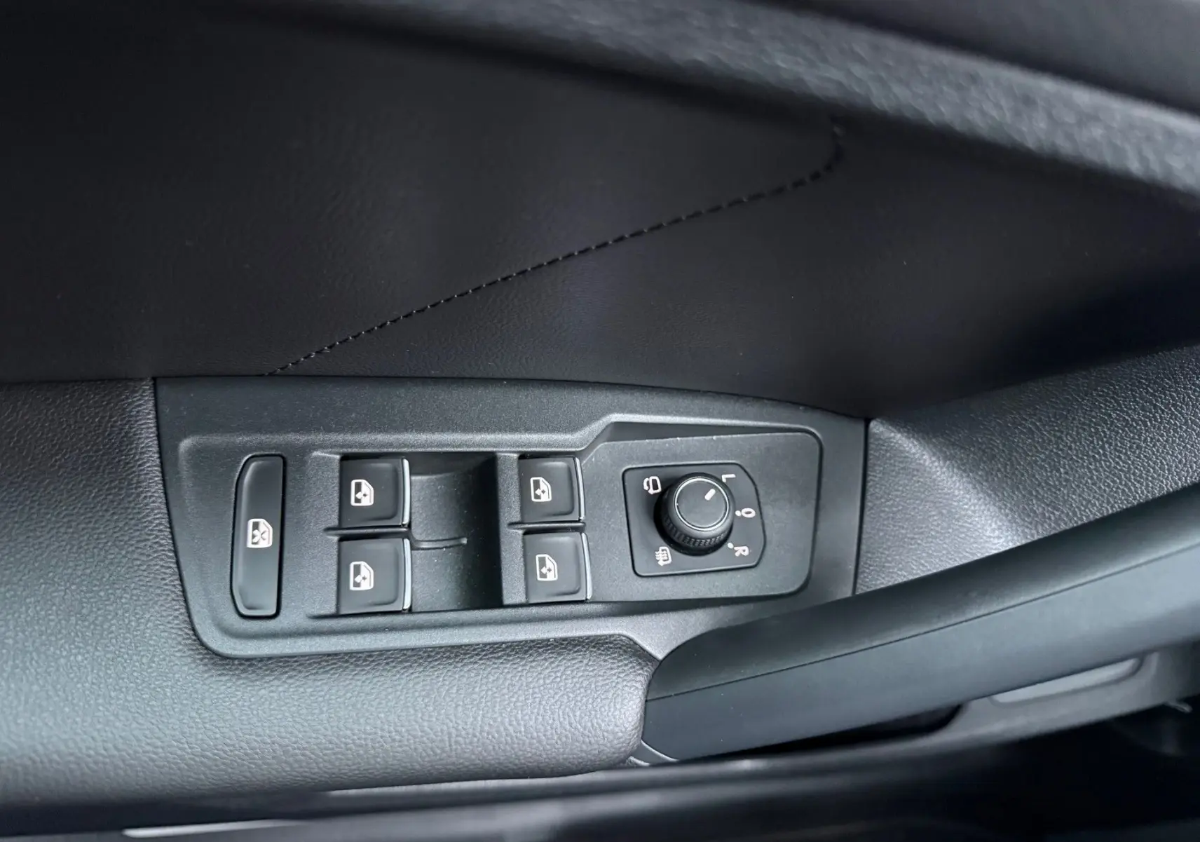 Gros plan sur les commandes des vitres et rétroviseurs côté conducteur d'un Volkswagen Tiguan bleu nuit 2022.