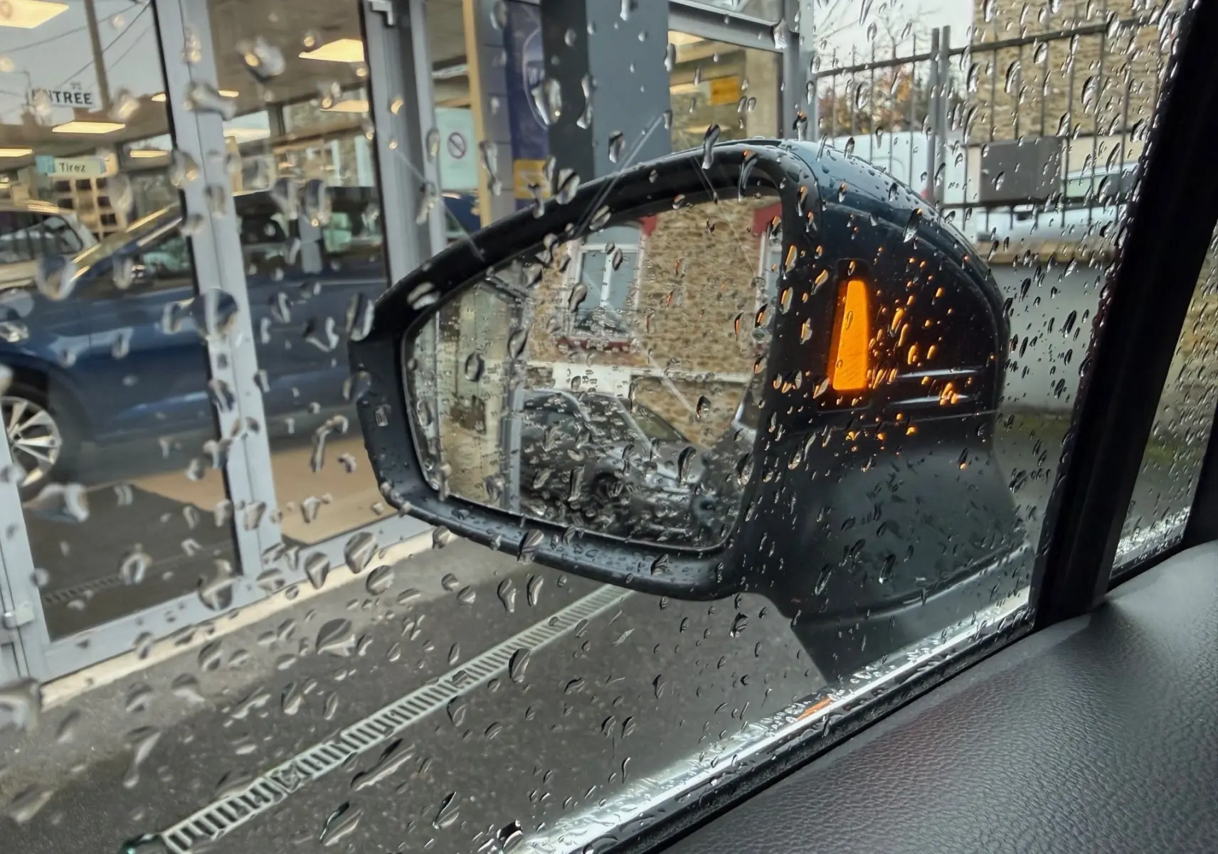 Rétroviseur côté droit du Volkswagen Tiguan bleu Night Shade avec clignotant orange sous la pluie.