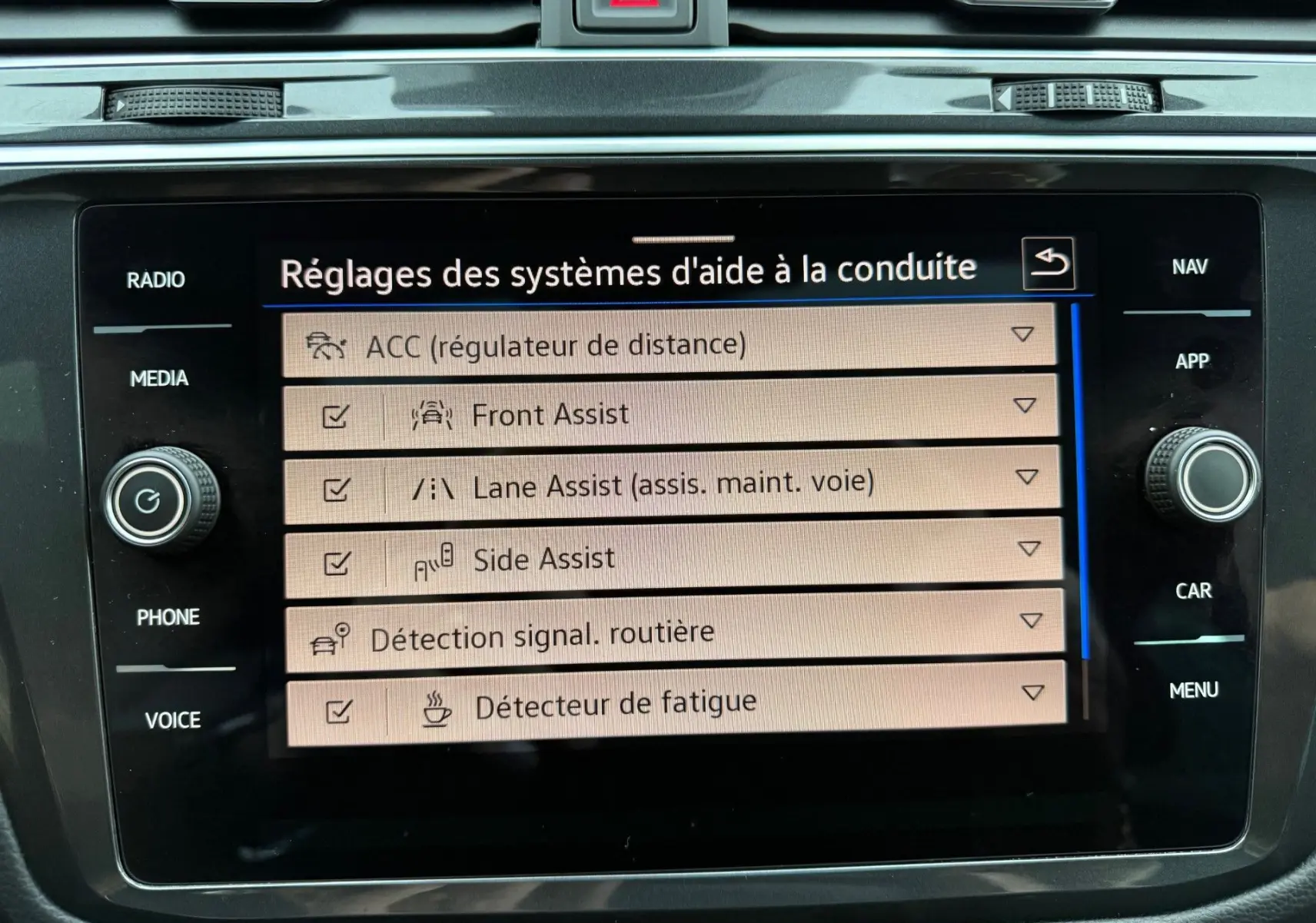 Écran tactile central du Volkswagen Tiguan 2022 affichant les réglages des aides à la conduite, intérieur noir.