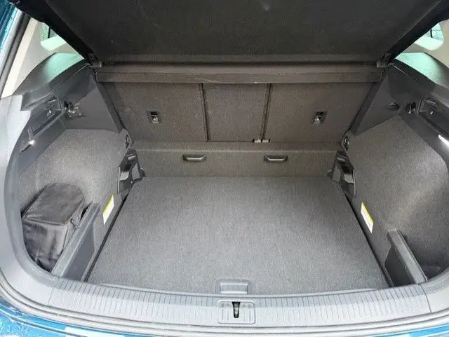 Coffre ouvert du Volkswagen Tiguan 2022 bleu Night Shade, montrant un espace de chargement propre et spacieux.