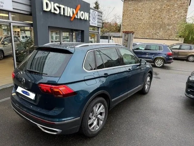 Vue 3/4 arrière droite d'un Volkswagen Tiguan 2022 bleu Night Shade avec toit noir et jantes argentées.