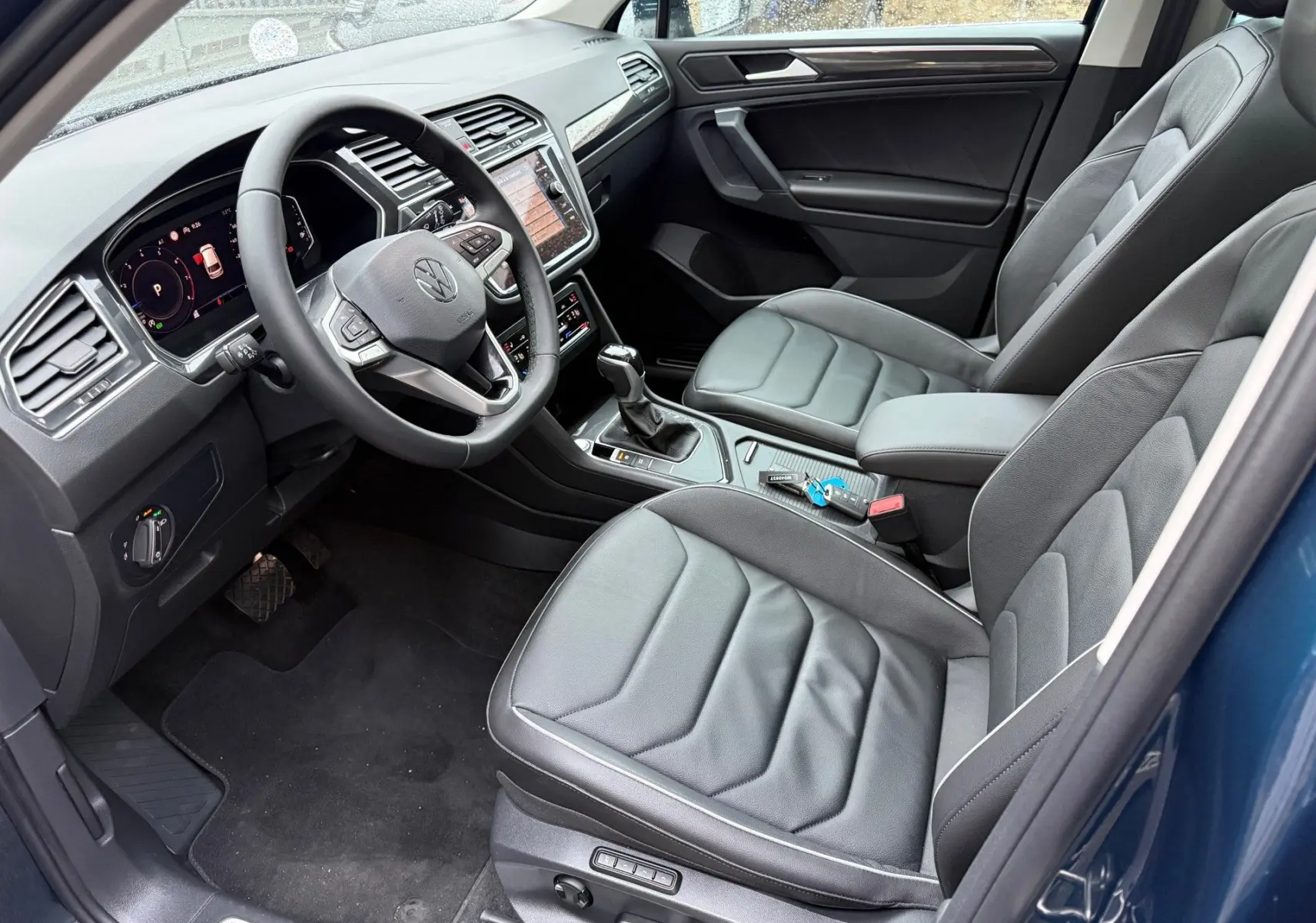 Intérieur du Volkswagen Tiguan 2022 en Night Shade Blue, vue côté conducteur avec sièges cuir noir et tableau de bord moderne.