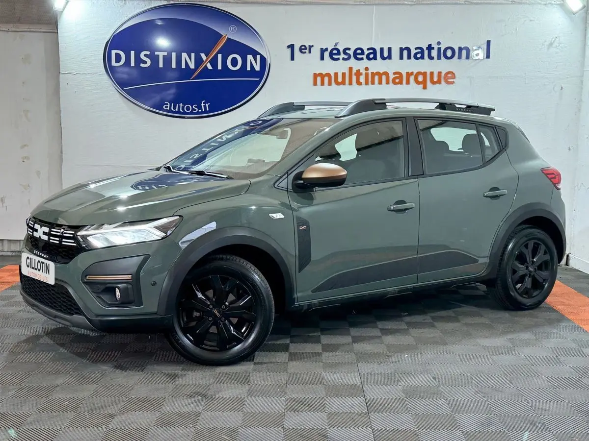 Vue 3/4 avant droite d'une Dacia Sandero Extreme+ TCe 110 2024 verte avec jantes noires et barres de toit.