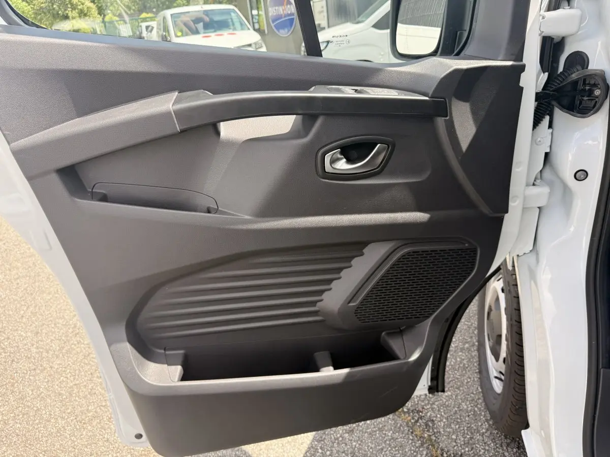Vue rapprochée de la porte avant droite blanche du Renault Trafic Fourgon 2025, montrant la poignée et le haut-parleur intégré.