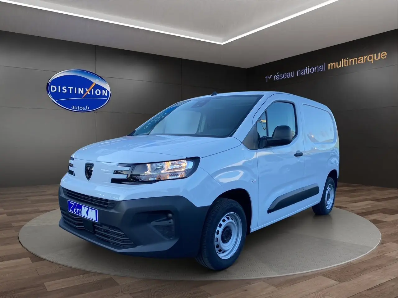 Peugeot Partner blanc vue 3/4 avant droit, fourgonnette utilitaire avec pare-chocs noirs et jantes acier simples.