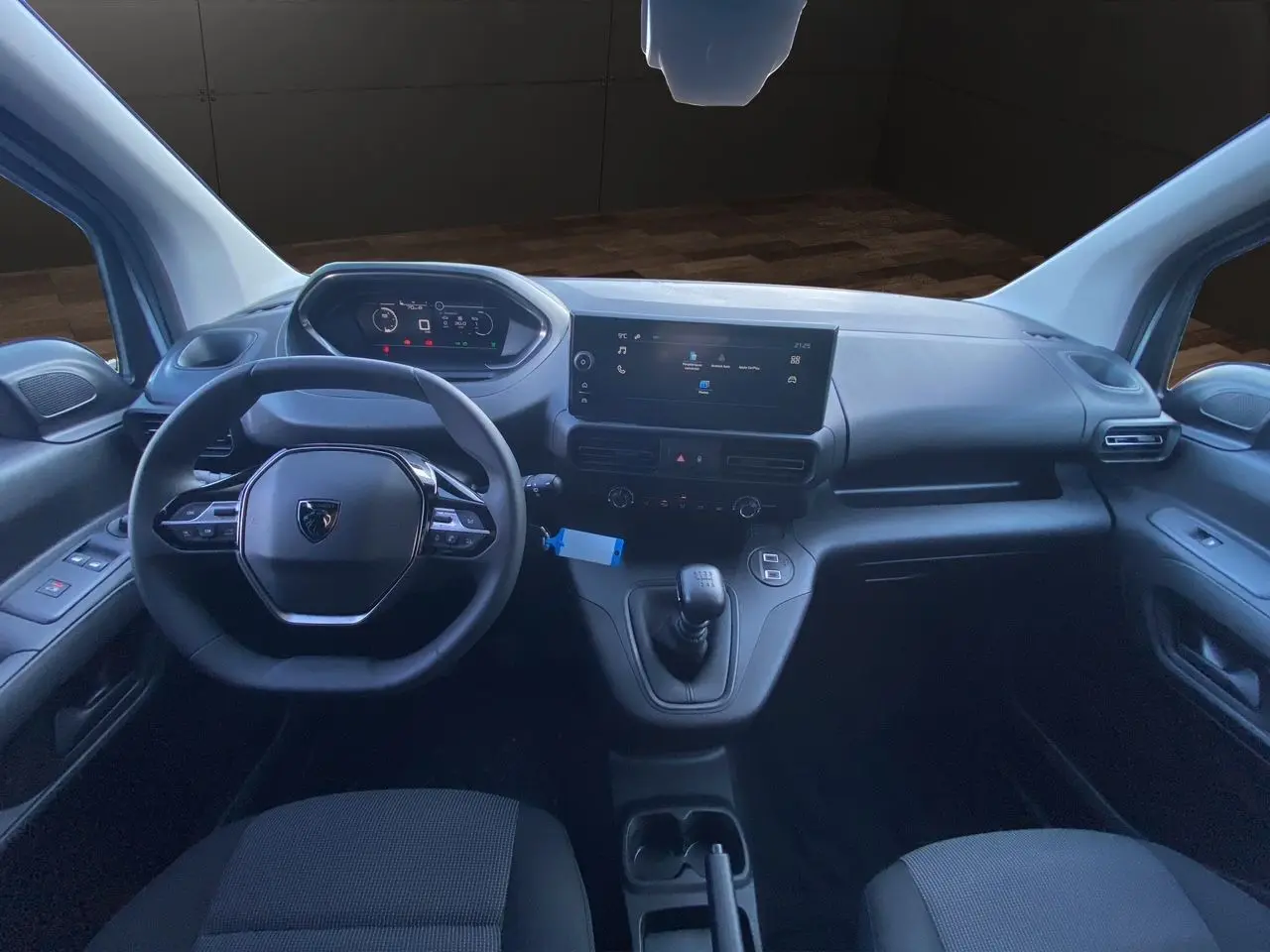 Intérieur du Peugeot Partner 2024 montrant le tableau de bord moderne avec écran tactile et volant multifonction noir.