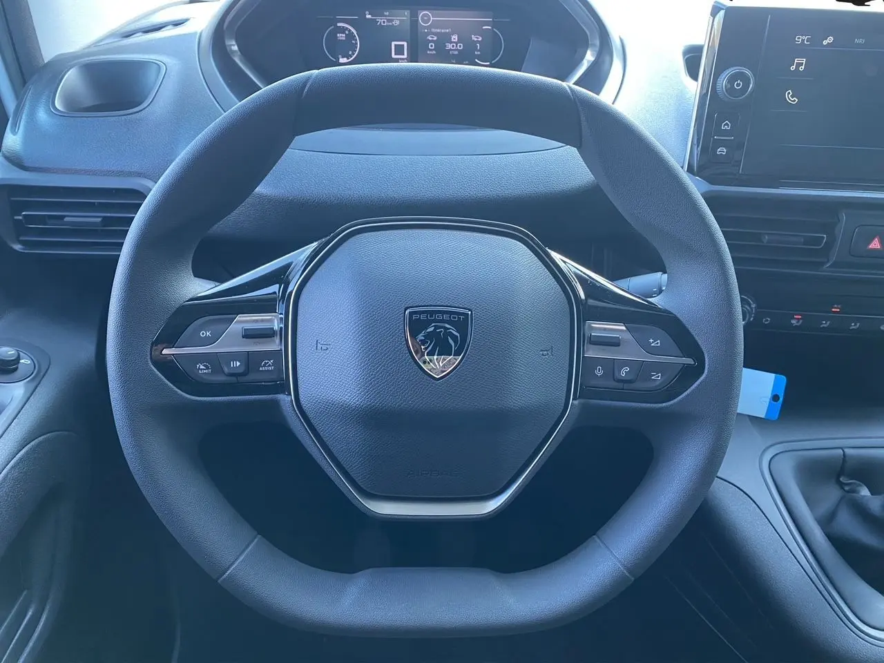 Vue rapprochée du volant noir du Peugeot Partner 2024 avec tableau de bord numérique et écran tactile visible.