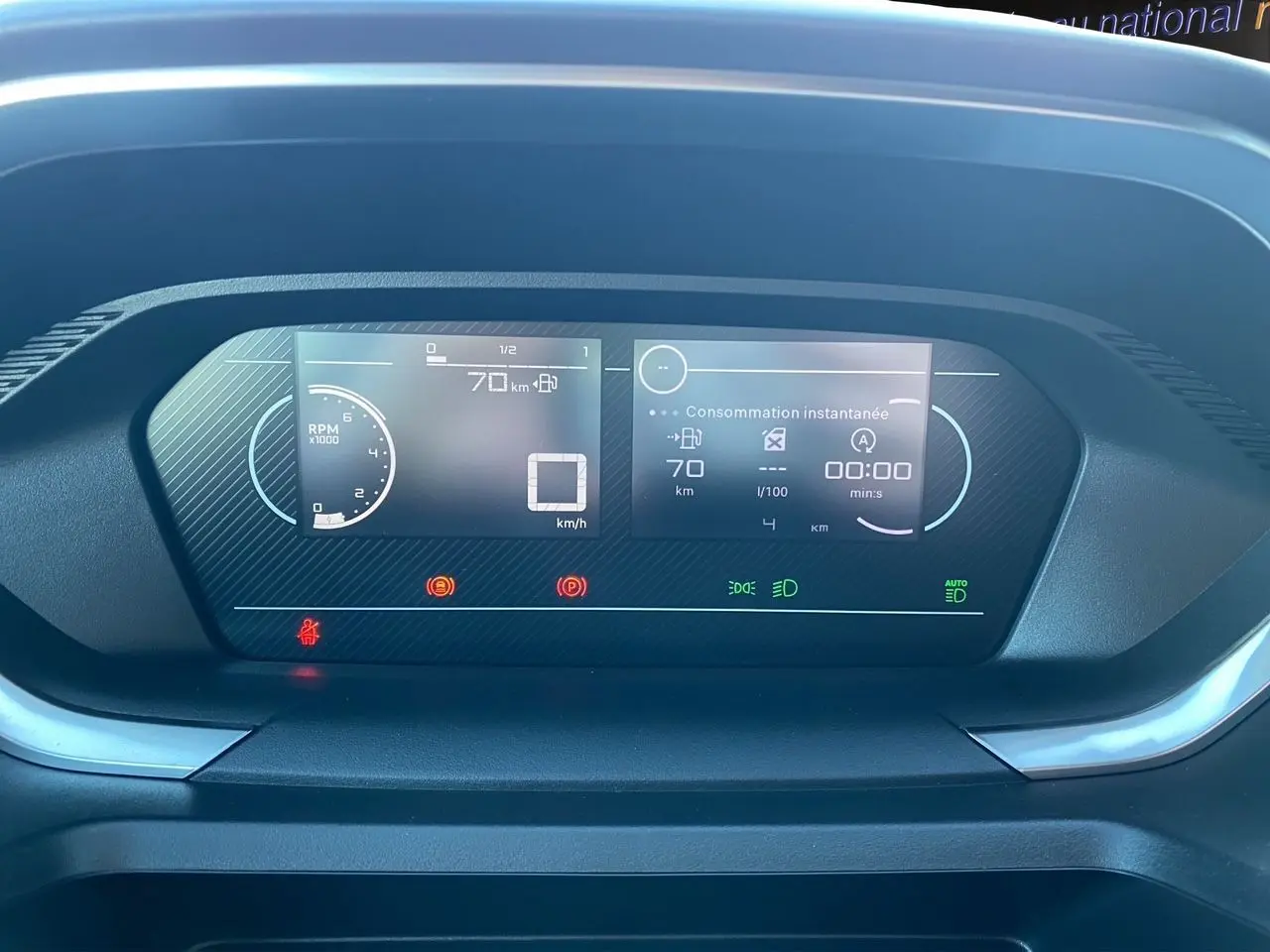 Tableau de bord numérique du Peugeot Partner 2024 affichant vitesse, consommation et compte-tours en vue frontale rapprochée.