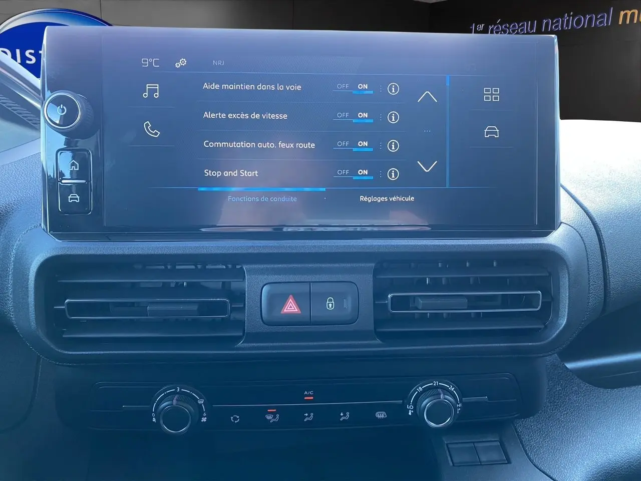 Écran tactile central du tableau de bord du Peugeot Partner blanc 2024 affichant les aides à la conduite.