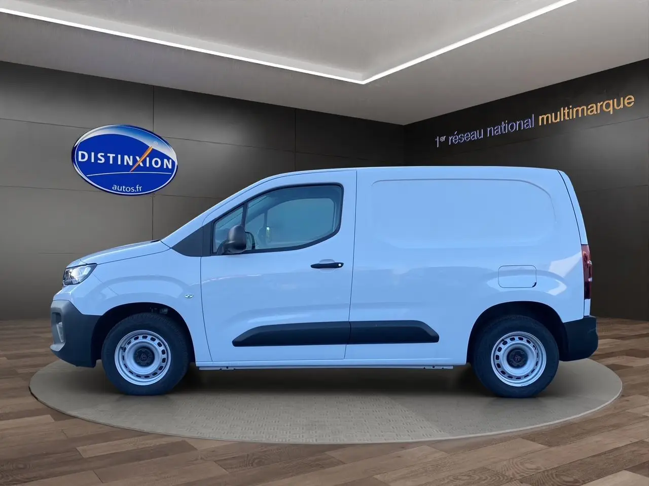 Peugeot Partner blanc en vue latérale droite, avec protections noires sur les portes et jantes acier simples.