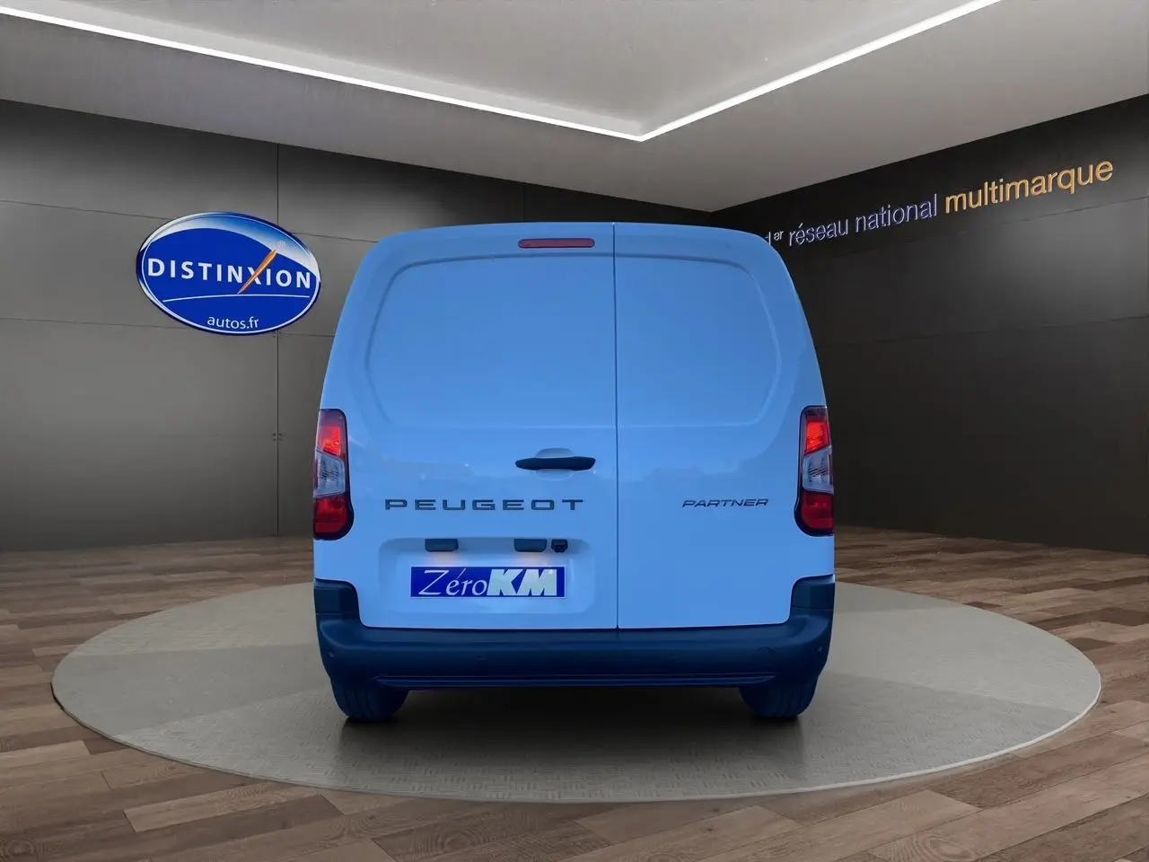 Vue arrière d'un utilitaire Peugeot Partner blanc avec portes battantes et logo distinctif sur fond showroom.
