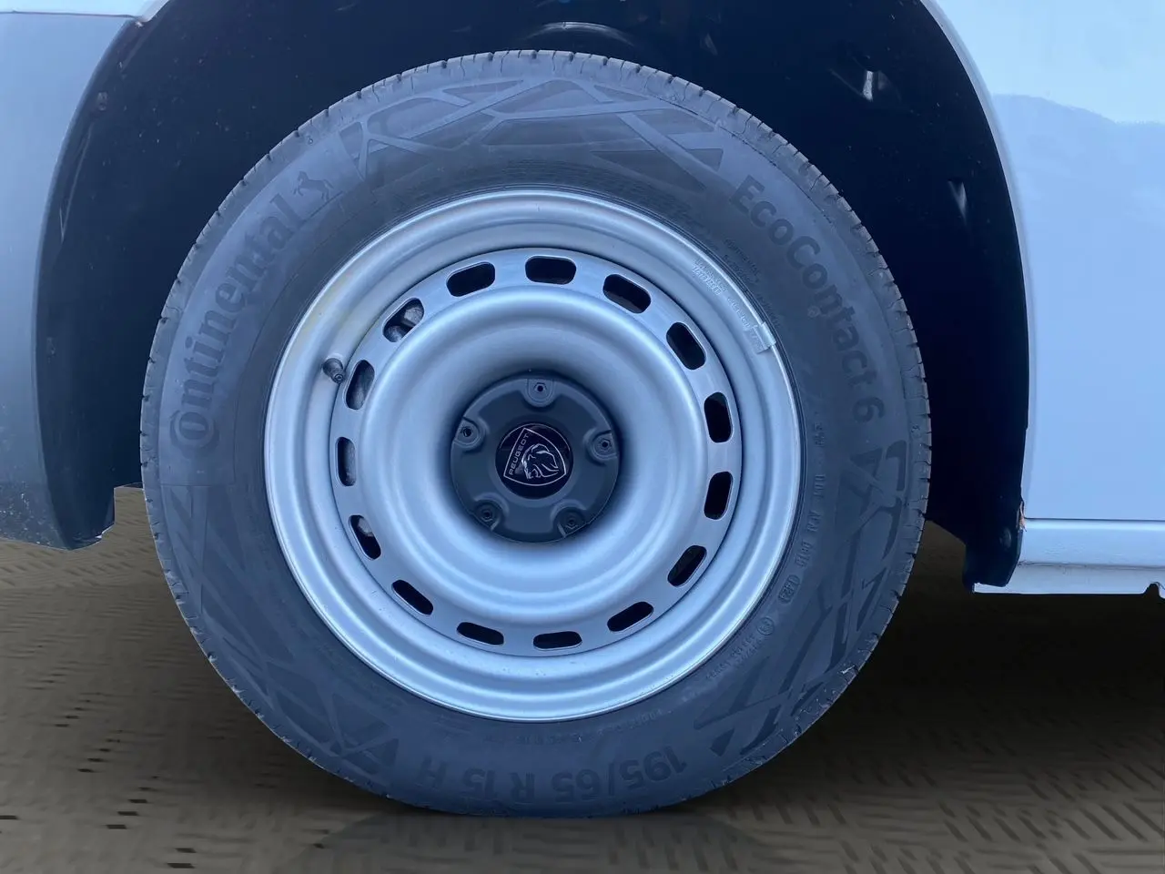 Gros plan sur la roue avant droite blanche du Peugeot Partner 2024 avec jante acier et logo lion central.