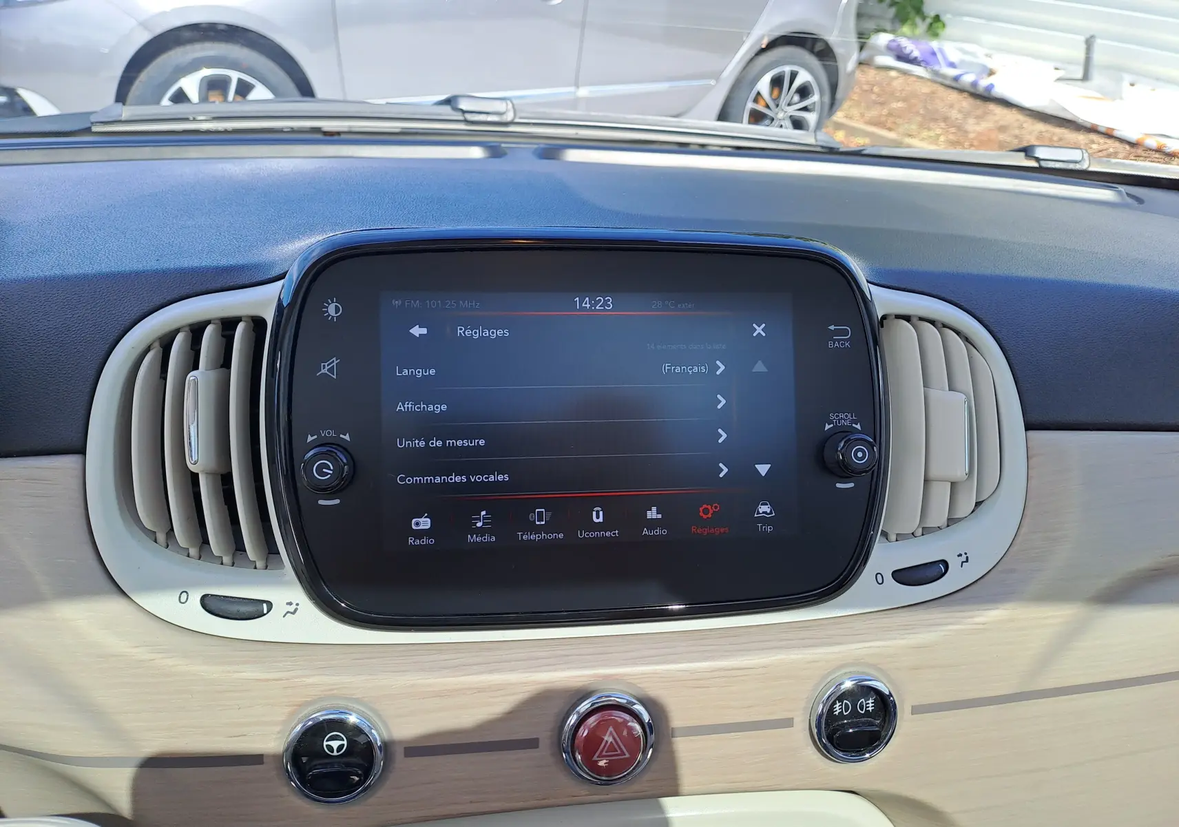 Vue rapprochée du tableau de bord beige et noir de la Fiat 500 blanche, mettant en valeur l'écran tactile central et les aérateurs.