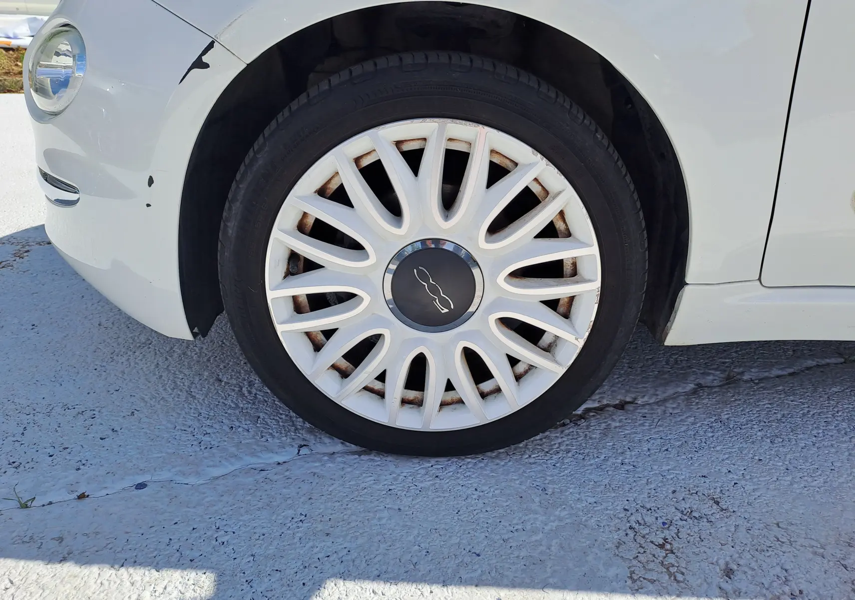 Gros plan sur la roue avant gauche blanche d'une FIAT 500 1.0 Hybrid 70CH DolceVita blanche avec jante à rayons fins.