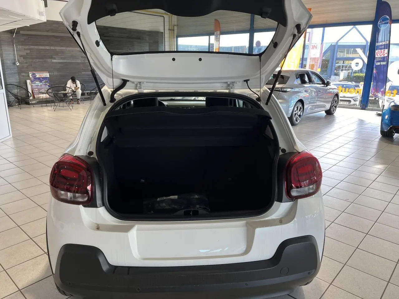 Vue arrière d'une Citroën C3 blanche 2024 avec coffre ouvert et feux arrière à effet 3D en showroom.