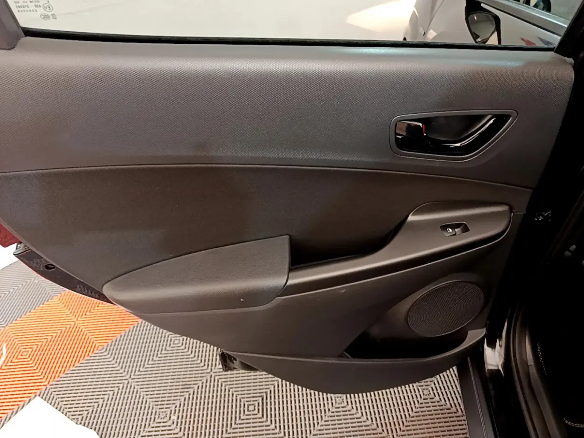 Gros plan sur la portière intérieure côté gauche noire du Hyundai Kona 2020 avec commande de vitre et haut-parleur intégré.