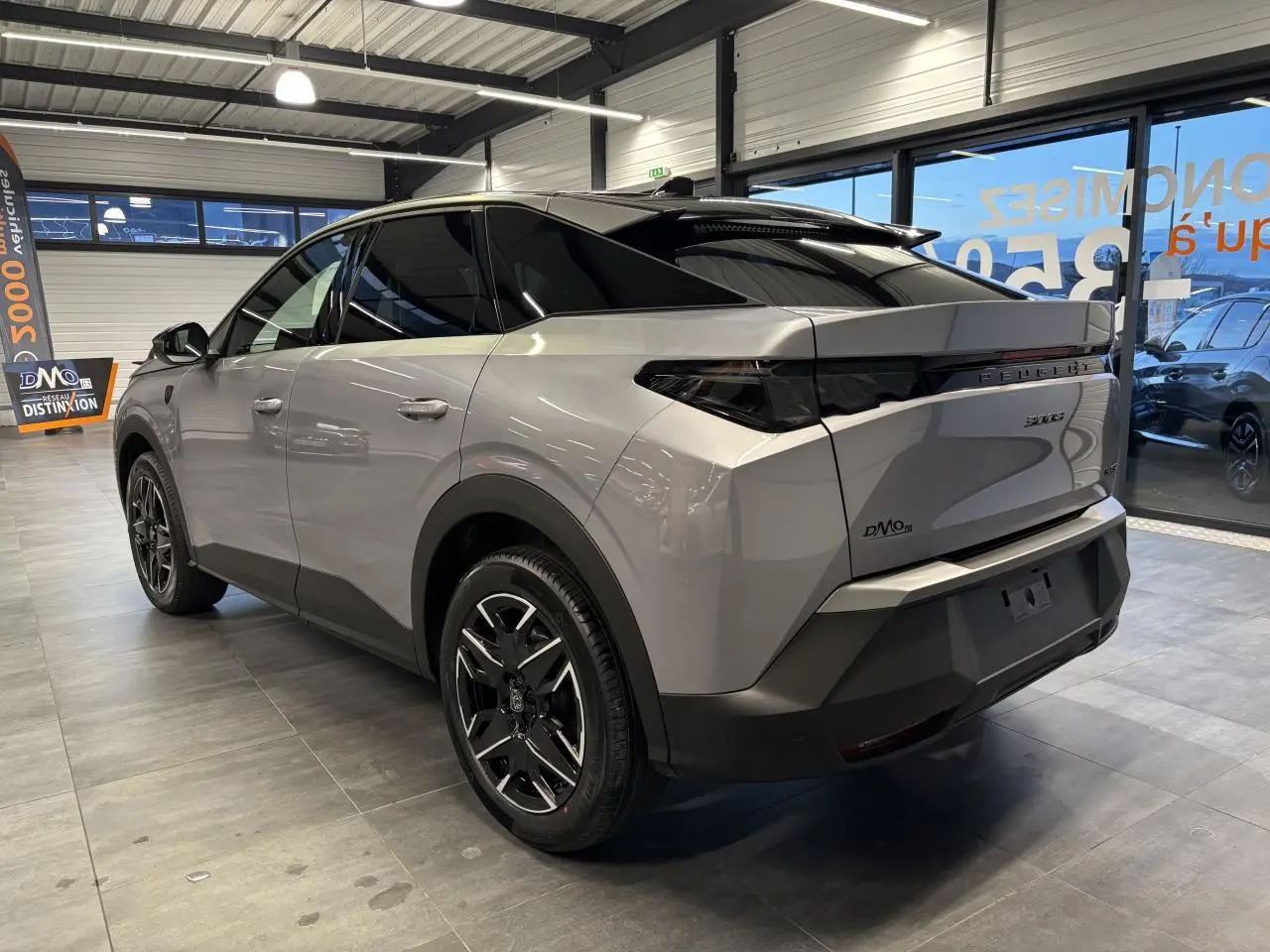 Vue 3/4 arrière droite du Peugeot 3008 gris Artense avec jantes alliage noires et toit noir en intérieur showroom.