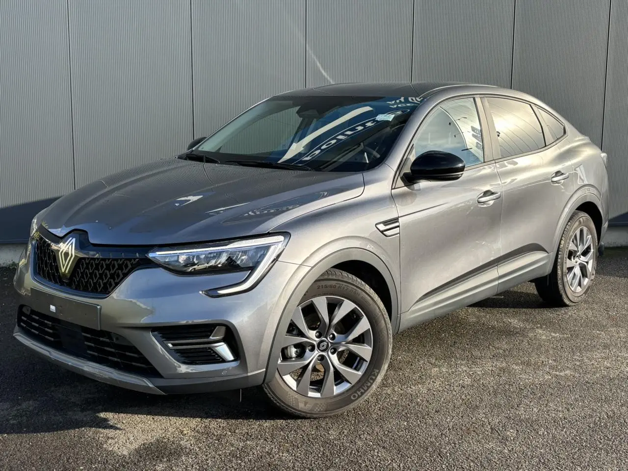 Renault Arkana gris métallisé en vue 3/4 avant droit, avec jantes alliage et calandre distinctive noire.