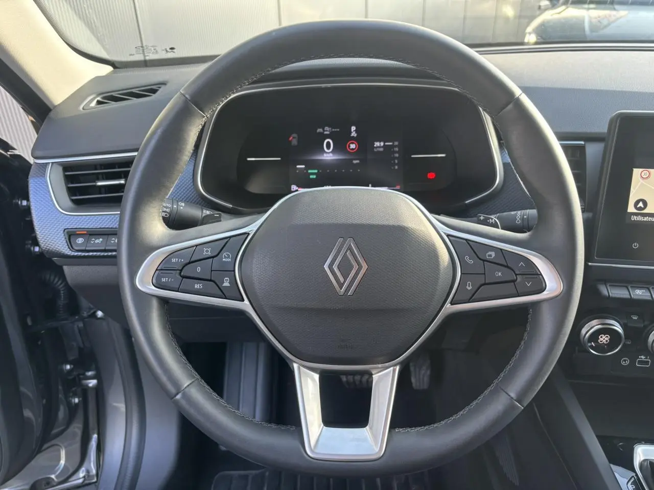 Vue frontale du volant noir de la Renault Arkana 2025 avec tableau de bord numérique et commandes intégrées.