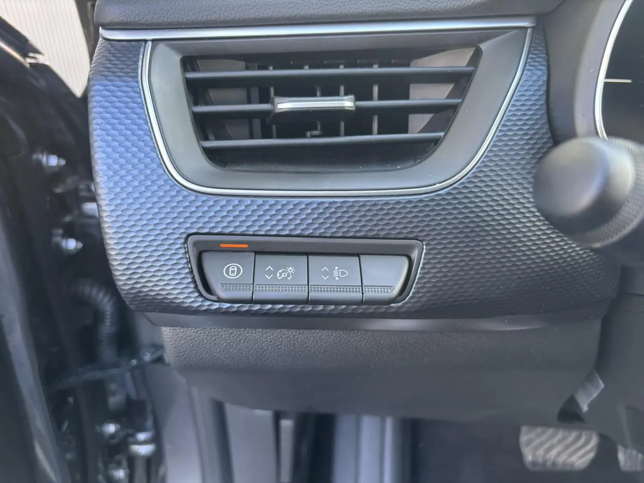 Détail des commandes d’éclairage et verrouillage sous la grille d’aération, intérieur gris du Renault Arkana 2025.
