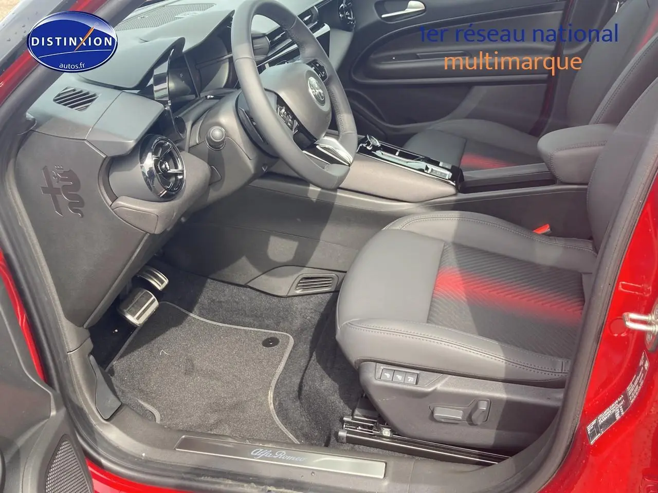 Intérieur côté conducteur d'Alfa Romeo Junior 1.2 hybride rouge/noir, siège électrique et volant multifonctions.