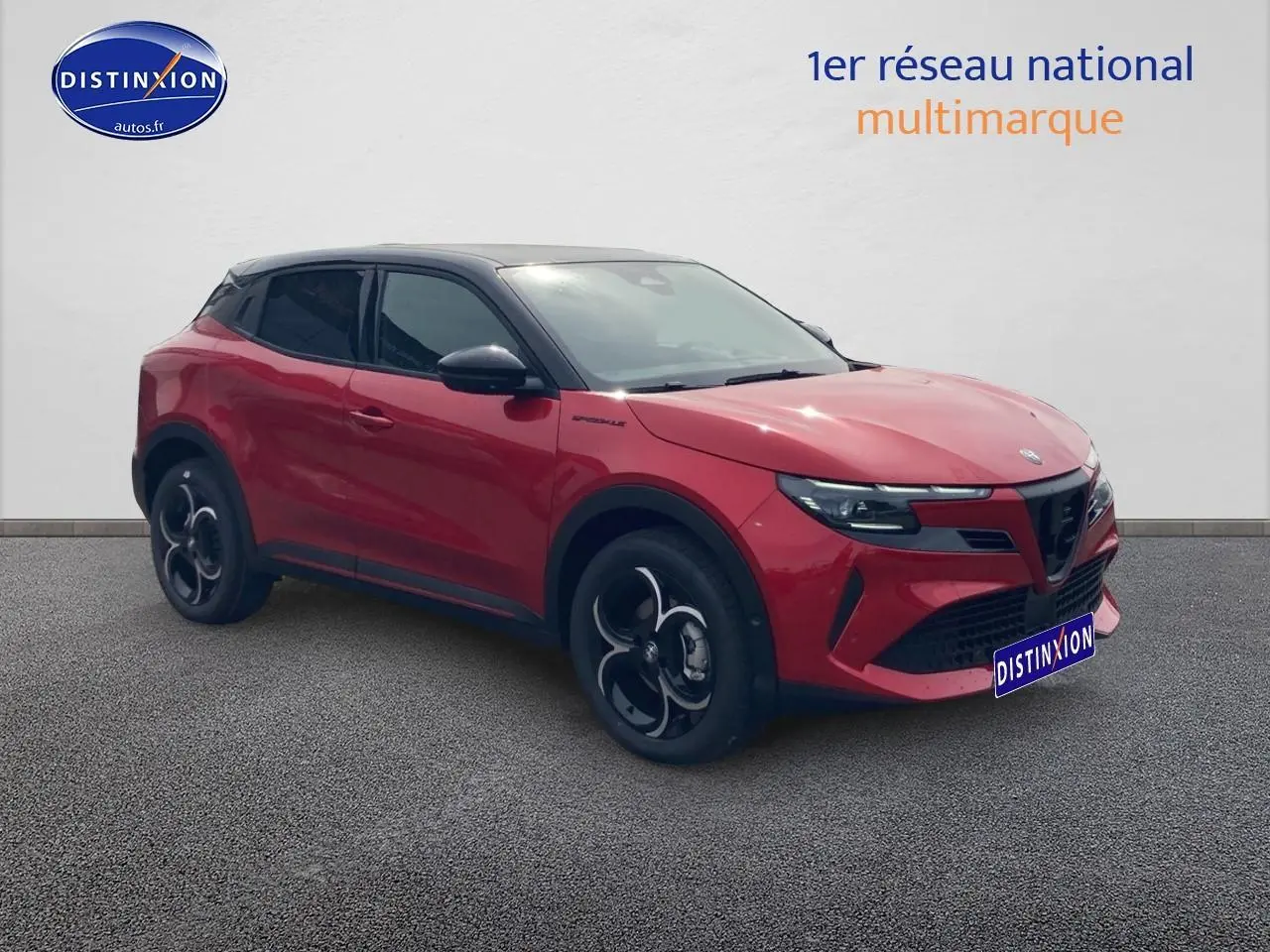 Vue 3/4 avant droite d'une Alfa Romeo Junior 1.2 hybride rouge et toit noir avec jantes alliage noires.