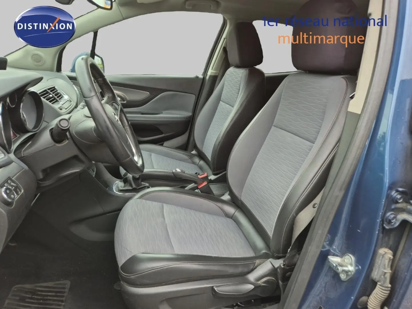 Vue intérieure côté conducteur de l'Opel Mokka bleu outremer, montrant les sièges avant et le volant multifonction cuir.