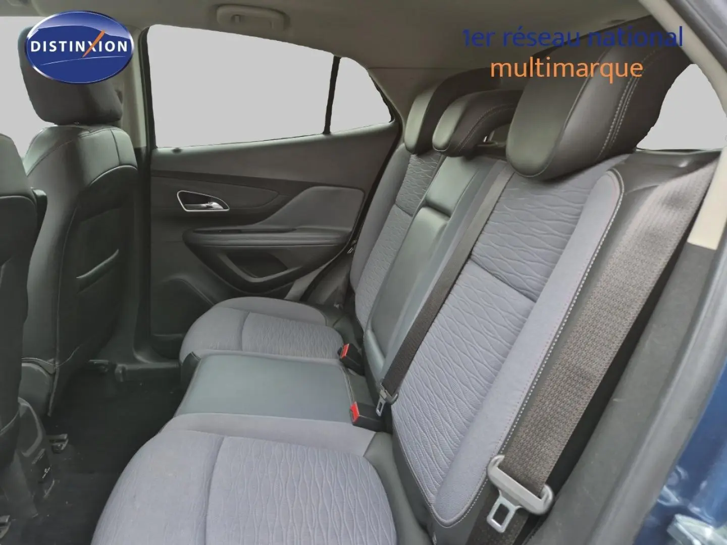 Vue intérieure arrière côté droit de l’Opel Mokka bleu outremer, montrant la banquette 3 places grise avec ceintures de sécurité.